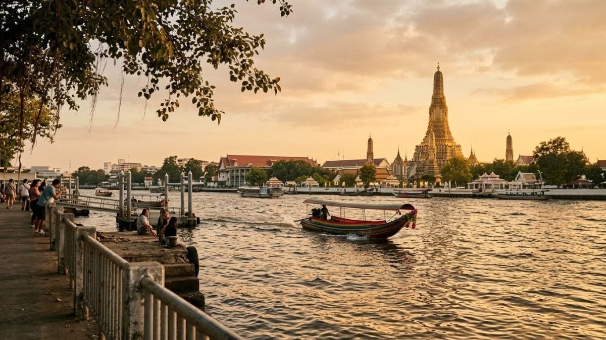 Riverside temple at sunset with a boat crossing the water, things to do in bangkok