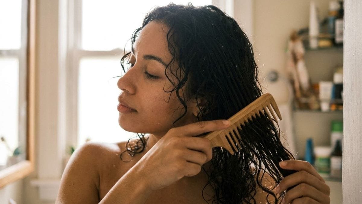 Woman gently combing damp hair with a wide-tooth comb, home remedies for dry hair