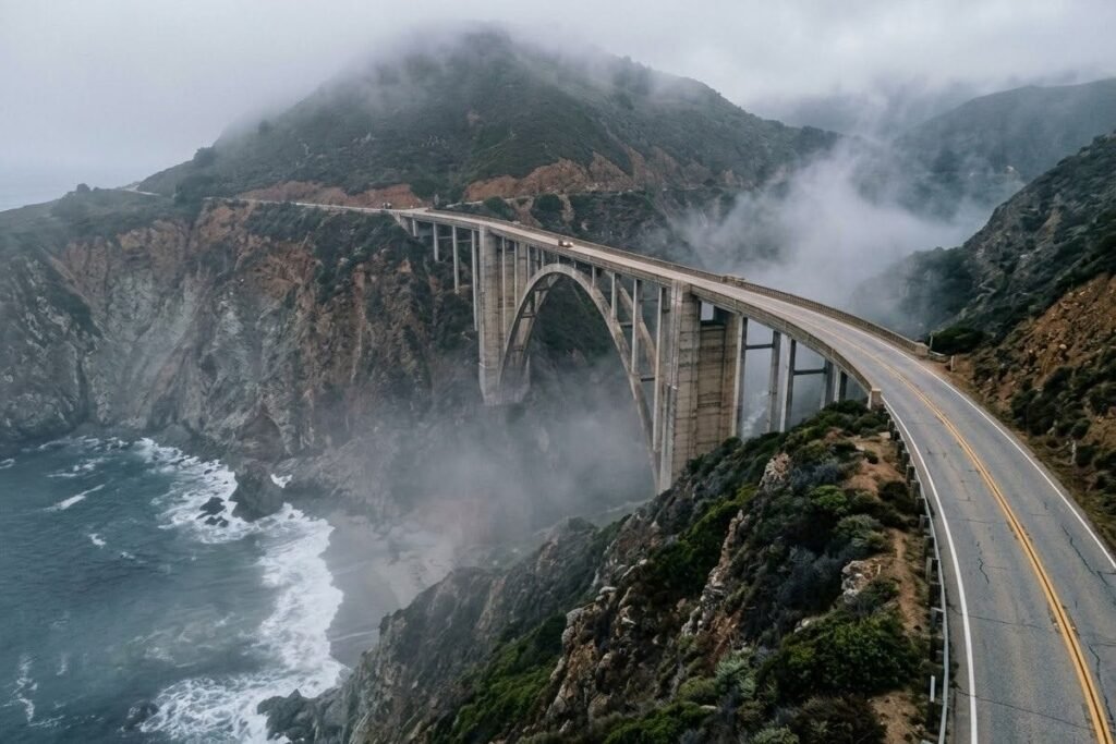 Concrete arch bridge on a rugged foggy coastline above the ocean