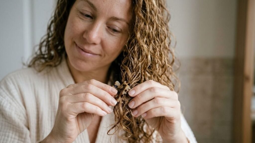 Hands sectioning curly hair with a clip, a step in how to detangle curly hair